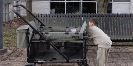 Young boy climbing into a sage-green Keenz VIVA stroller wagon