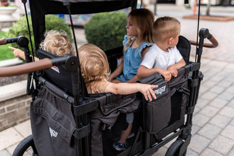 four passenger black Keenz stroller wagon with top cover houses four children who look out to the cobbled streets of the city