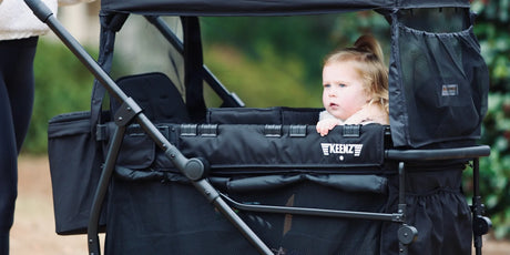 Parent guiding a stroller wagon along a family outing path